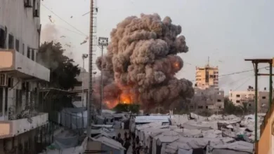 A wide view of Gaza City with damaged buildings, humanitarian aid trucks, and symbolic peace imagery such as a white dove or ceasefire negotiations. (Use a neutral, non-graphic image.)