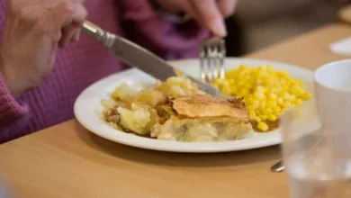 An older woman enjoying a healthy meal during daylight hours while a clock highlights an 8–9 hour eating window, representing time-restricted eating for brain health.