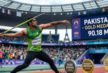 Arshad Nadeem competing in the javelin throw qualification round with the Pakistan flag in the background and a packed Commonwealth Games stadium.