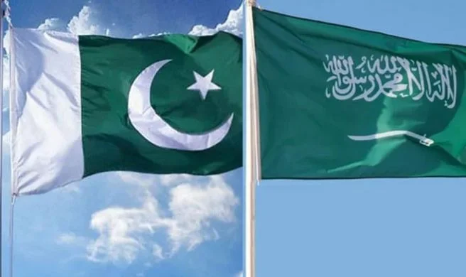 Pakistan and Saudi Arabia flags with U.S. dollar currency and financial charts representing the three-year extension of Pakistan's $5 billion Saudi loan.