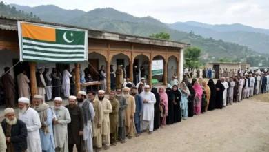 Voters queue outside a polling station during the 2026 Azad Kashmir general elections in Mirpur Division as security personnel monitor the voting process.