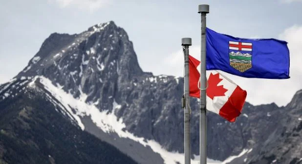 Canadian and Alberta flags flying in the breeze with Wedge Mountain in the background in Kananaskis, Alberta, amid debate over Alberta independence.